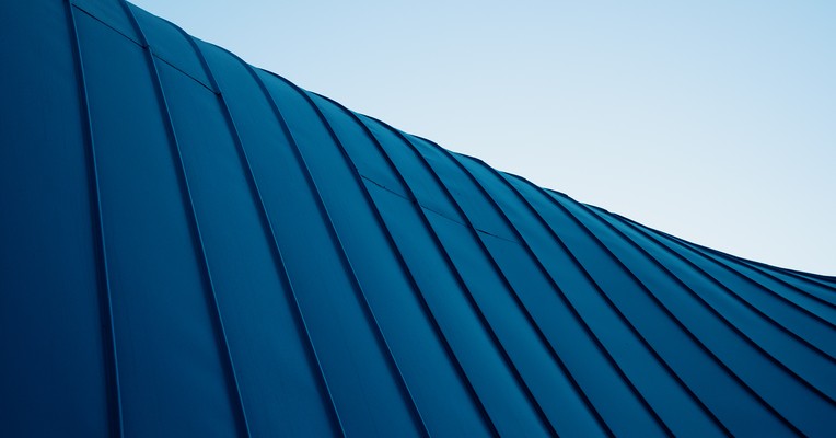 Unsanctioned agent data connections: a curved blue metal facade of fanning vertical seams against a pale sky