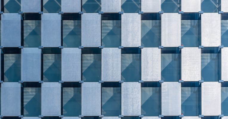 AI behaviour verification evidence for auditors and boards: an orderly grid of glass office windows in blue and grey
