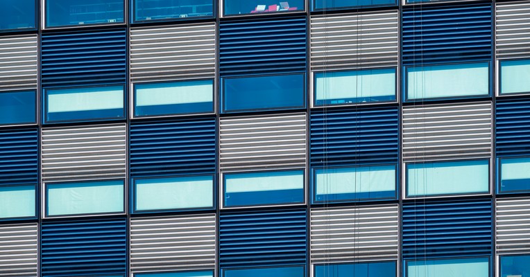 AI behaviour verification evidence: an orderly grid of repeating blue and grey window modules across a building facade