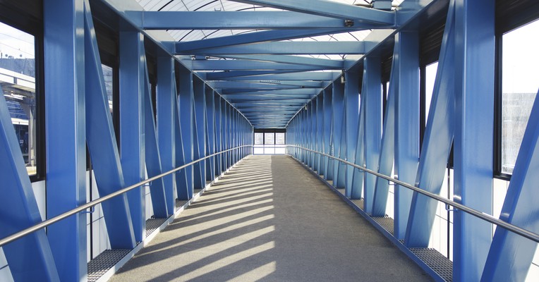 Securing long-running AI agents: an enclosed blue steel walkway receding into the distance with light and shadow across the floor